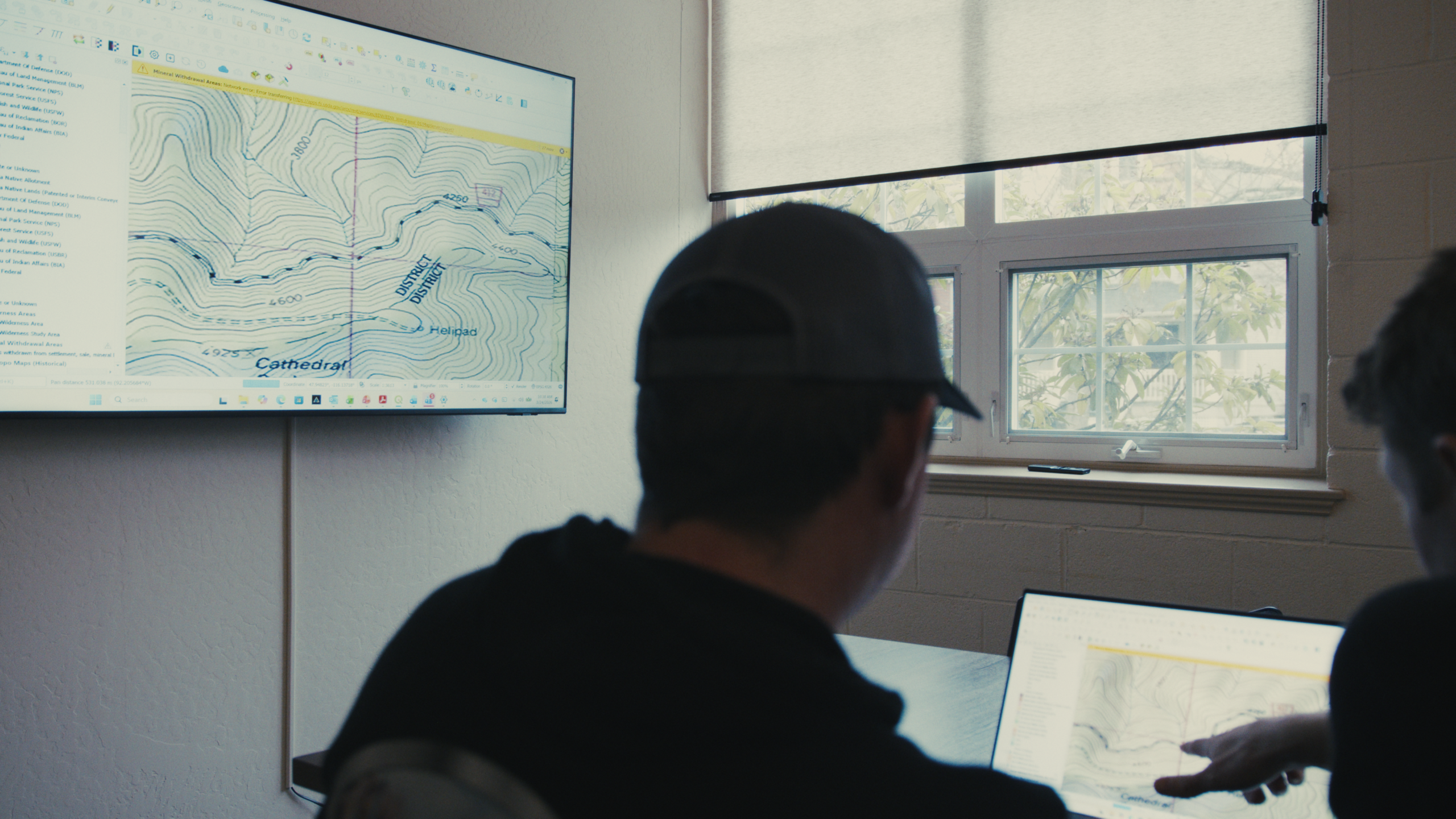 Two people looking at maps on a computer screen
